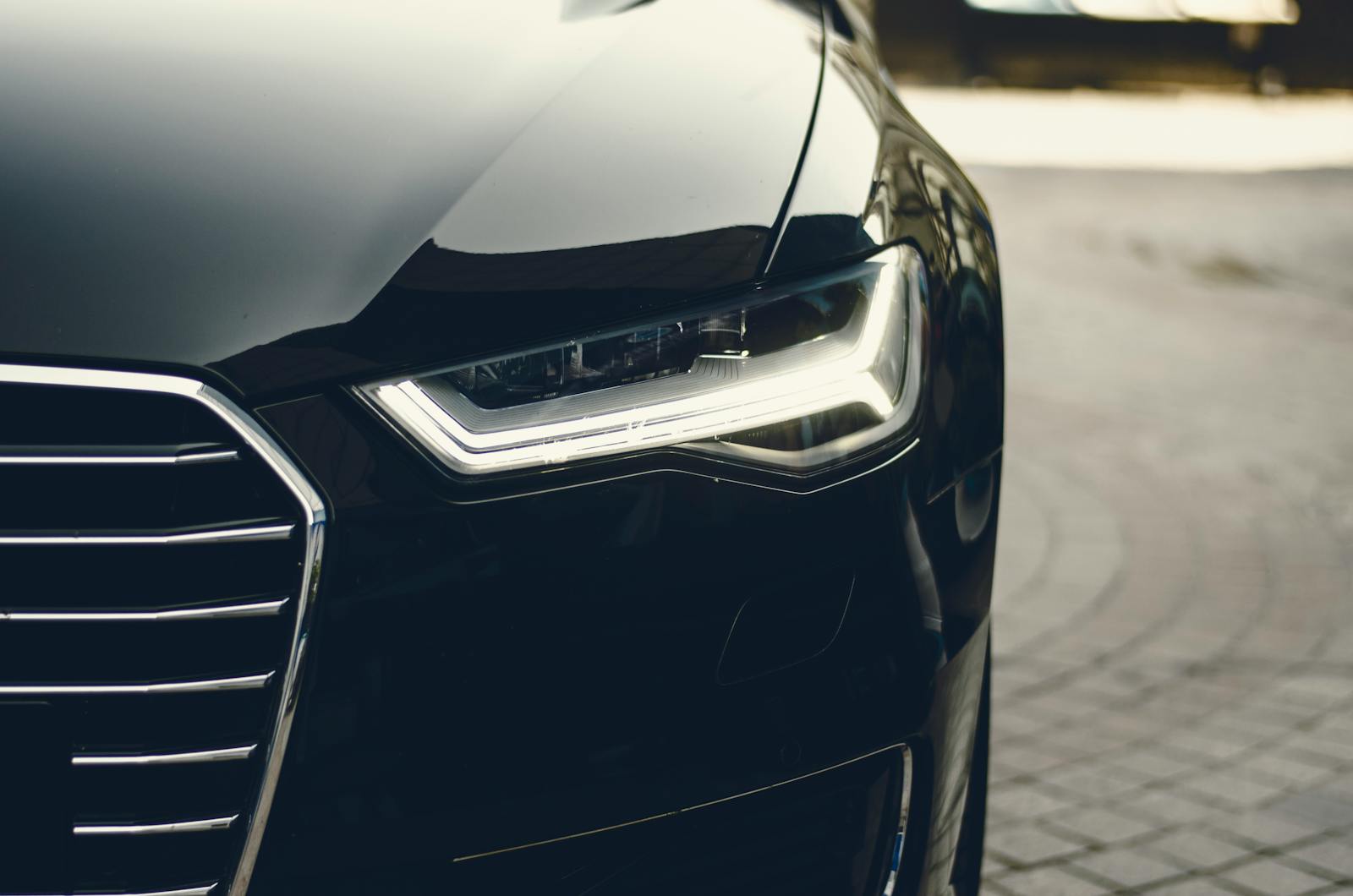 auto, sleek, modern luxury car showcasing its chrome detailing and LED headlights on a city street.